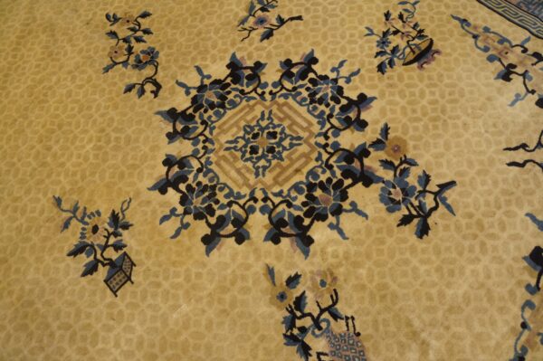 Gold rug detail showing dark blue and black scrolling florals surrounding a geometric central motif.