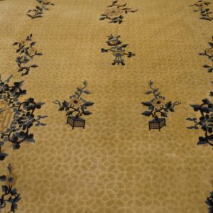 Yellow low-pile rug featuring scattered potted plants and elaborate blue and navy floral medallions.