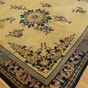 Traditional rug with a tan field, dark blue floral motifs, and detailed multi-layered borders on wood plank flooring.