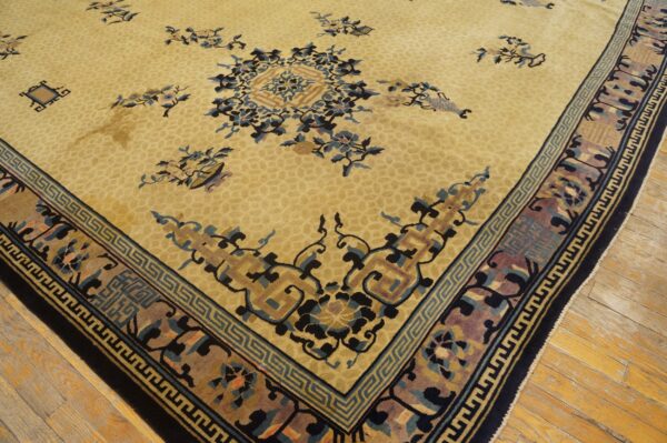 Traditional rug with a tan field, dark blue floral motifs, and detailed multi-layered borders on wood plank flooring.