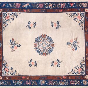 Ornate cream rug with indigo, terracotta, and pink floral patterns and a wide multi-layered border.