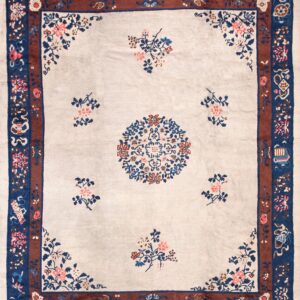 Pale beige rug with a central floral medallion and border in deep blue, rust, and pink.