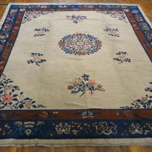Cream floral rug featuring a blue medallion and intricate blue and brown multi-band borders on hardwood.