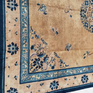Close up of a beige rug featuring elaborate blue floral motifs, borders, and a partial medallion.