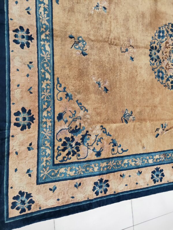 Close up of a beige rug featuring elaborate blue floral motifs, borders, and a partial medallion.