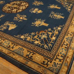 Low-pile dark blue rug with scattered tan floral motifs and a detailed border on rustic wood flooring.