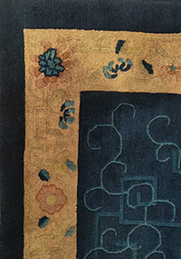 Deep blue rug field with teal scrolls meets a golden border featuring scattered floral and leaf designs.