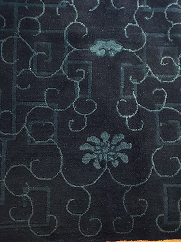 Dark indigo rug featuring low-contrast teal geometric fretwork and elaborate scrolling botanical motifs.