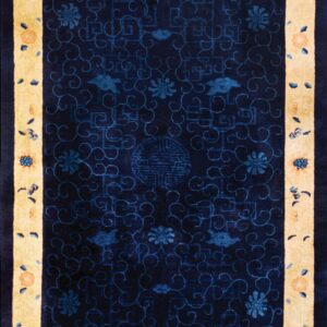 Navy blue rug with a light yellow border and floral designs in blue and muted orange.
