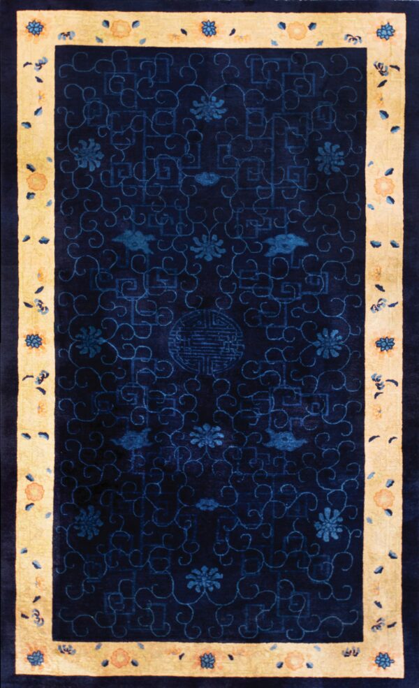 Navy blue rug with a light yellow border and floral designs in blue and muted orange.