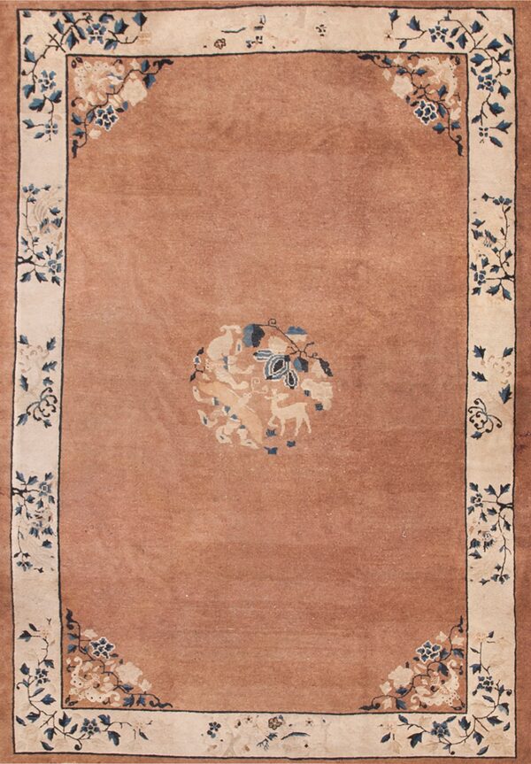 Low pile rug with a dusty rose field, a central deer medallion, and a cream border with blue florals.