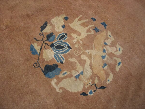 Muted tan rug detail showing a round pattern of blue foliage and light cream animal figures.