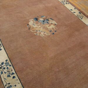 Low-pile russet rug with a central beige and blue animal motif bordered by dark floral vines on wood.