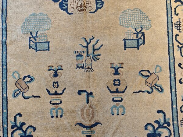 Beige rug detail featuring stylized figures and trees patterned in dark blue and light blue.
