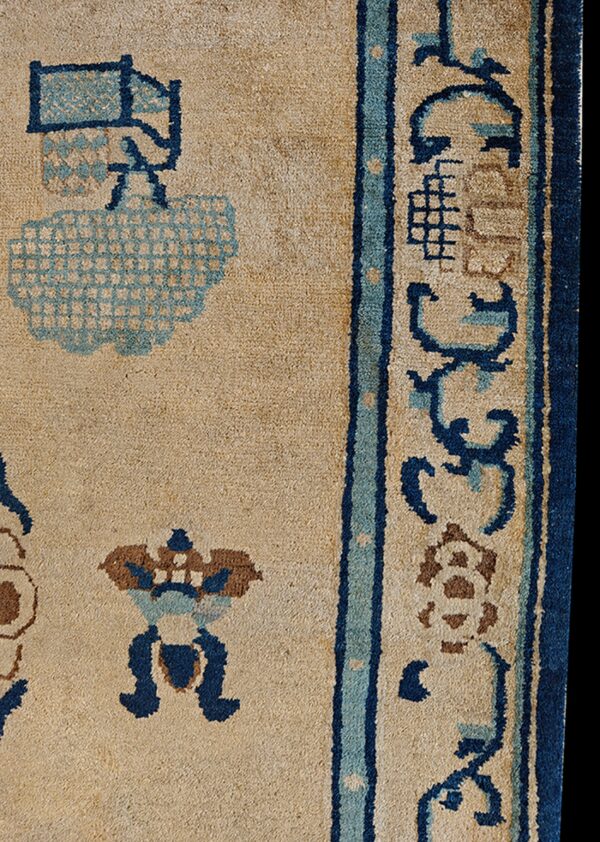 Beige rug detail featuring dark blue, teal, and brown angular motifs near a thick vertical border.