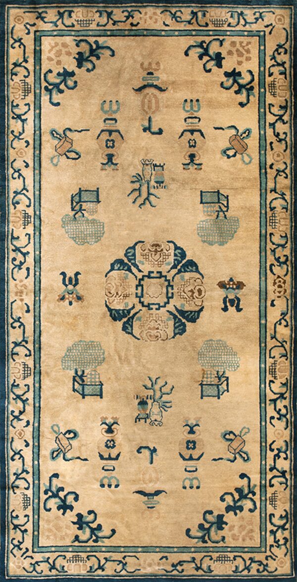 Light brown rug with blue and teal symbolic designs, framed by a thick dark blue scrolling border.