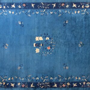 Saturated blue rug with a navy border, featuring delicate light blue and peach bird and floral patterns.