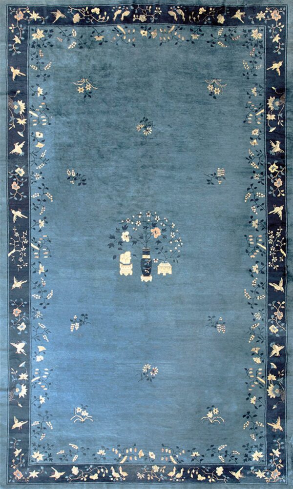 Teal rug featuring a central vase and scattered flowers, framed by a dark blue border with birds and vines.