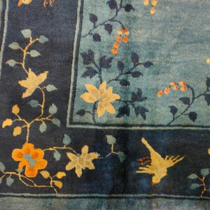 Teal rug field and navy border with stylized yellow, gold, and orange floral and bird motifs.
