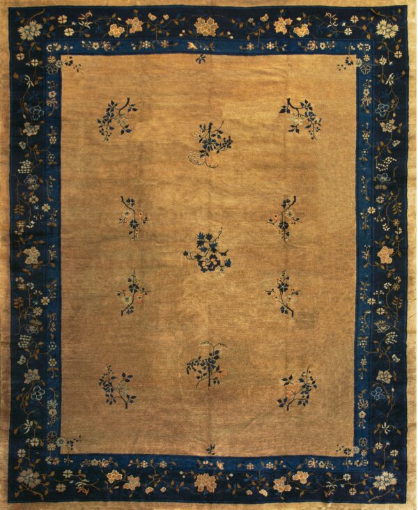 A golden rug with scattered blue floral sprigs and a wide dark blue border featuring winding flowers.