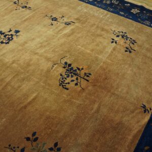 Golden low-pile rug featuring scattered blue floral motifs and a complex navy blue patterned border on a wood floor.
