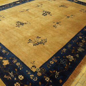 Golden tan rug featuring scattered blue floral designs and a wide navy blue botanical border on wooden flooring.