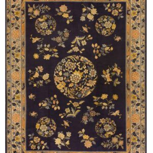 Dark navy rug featuring scattered yellow and peach floral sprays and medallions, framed by an intricate bordered design.