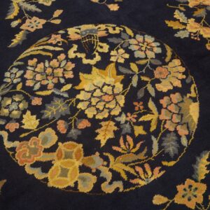 Navy rug with a detailed gold and coral floral medallion and scattered botanical designs.