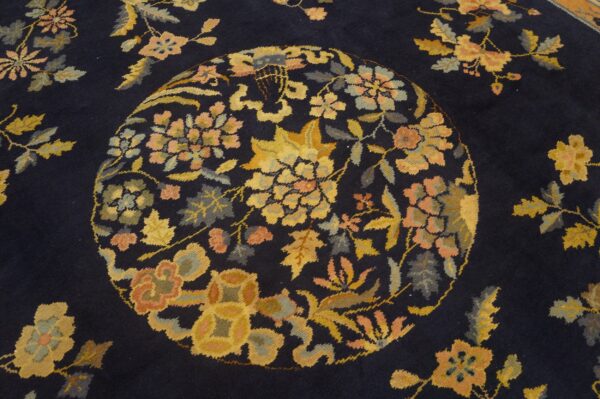 Navy rug with a detailed gold and coral floral medallion and scattered botanical designs.