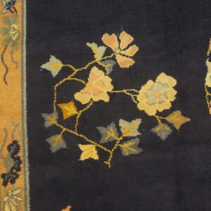 Navy rug field with yellow, peach, and gray floral patterns beside a broad mustard and cream border.