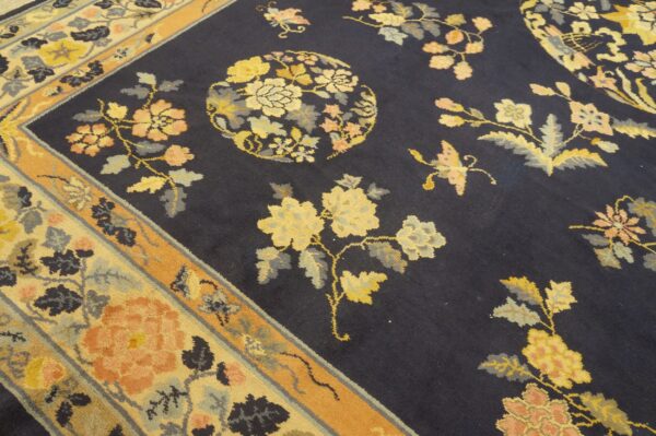 Navy area rug featuring scattered yellow and peach flowers and leaves bordered by orange and cream bands.