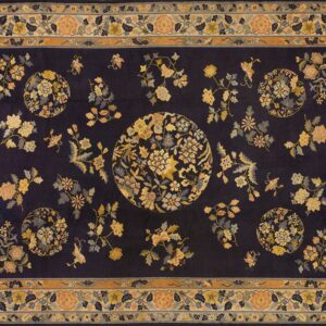 A dark blue rug featuring a scattered floral and medallion pattern in gold, peach, and gray with a wide ornate border.