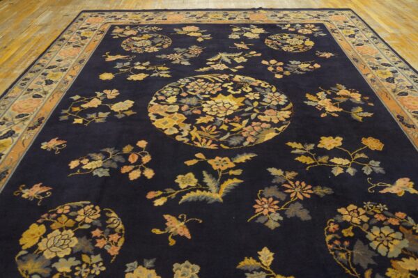 Dark blue rug featuring ornate yellow and peach floral medallions on wide wood planks.
