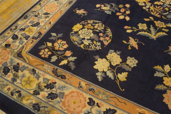 Navy blue rug with floral sprays and a circular medallion rests on distressed wood planks.