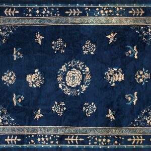 Navy blue rug with light beige floral patterns, a central rosette, and a decorative Greek key border motif.