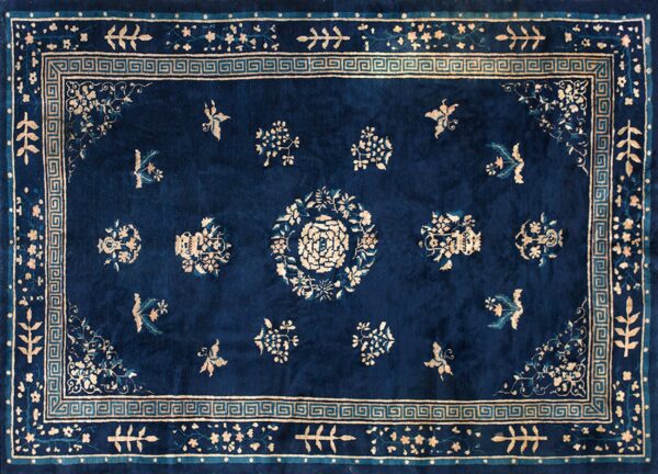 Navy blue rug with light beige floral patterns, a central rosette, and a decorative greek key border motif.