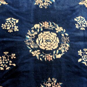 Close-up of a deep blue rug featuring scattered cream and light blue stylized floral medallions on a high pile.