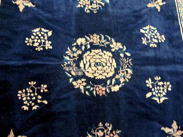 Close-up of a deep blue rug featuring scattered cream and light blue stylized floral medallions on a high pile.