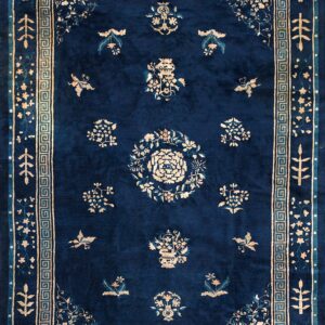 Deep blue rug with cream and teal floral designs, surrounded by a distinct Greek key border.