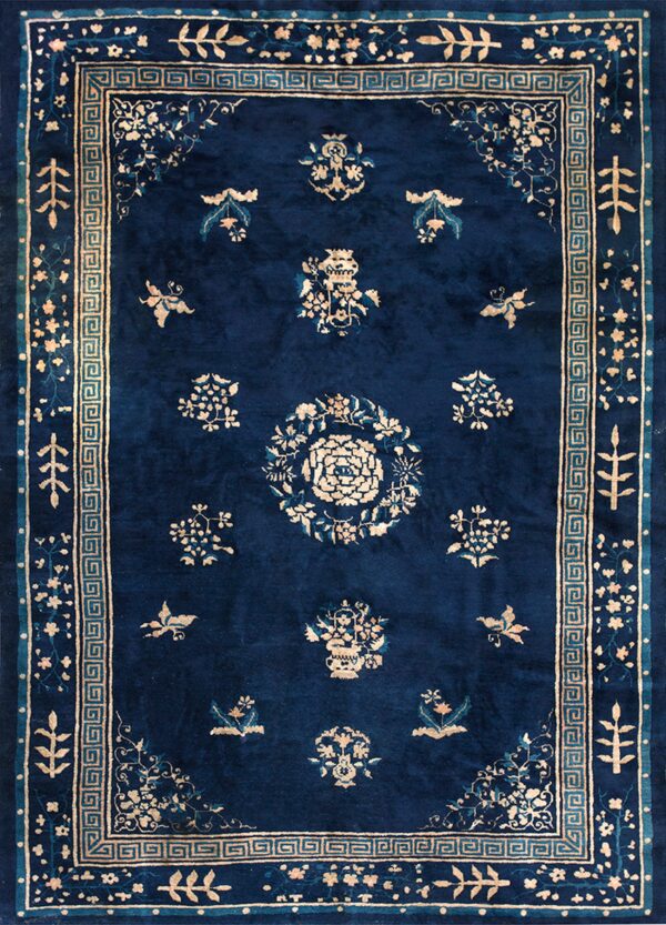 Deep blue rug with cream and teal floral designs, surrounded by a distinct greek key border.