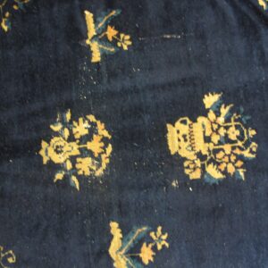 Dark blue rug detail featuring golden yellow and teal floral motifs and a geometric border.