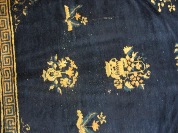 Dark blue rug detail featuring golden yellow and teal floral motifs and a geometric border.