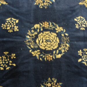 Textured navy blue rug with stylized yellow and teal floral patterns visible in a close-up view.