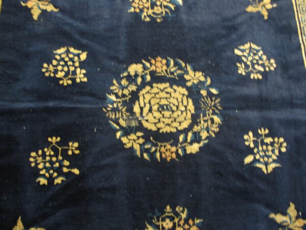 Textured navy blue rug with stylized yellow and teal floral patterns visible in a close-up view.
