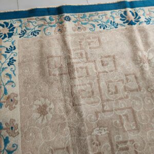 Light pink rug with geometric pattern and teal floral border visible on white tile flooring.