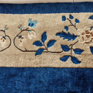 Textured blue rug with a beige center stripe featuring sculpted blue, cream, and brown floral patterns.