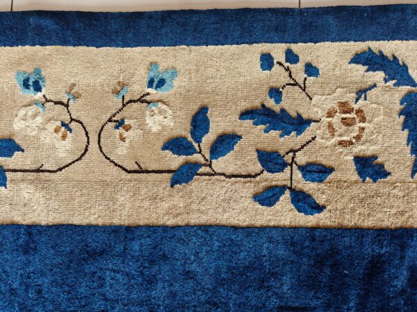 Textured blue rug with a beige center stripe featuring sculpted blue, cream, and brown floral patterns.