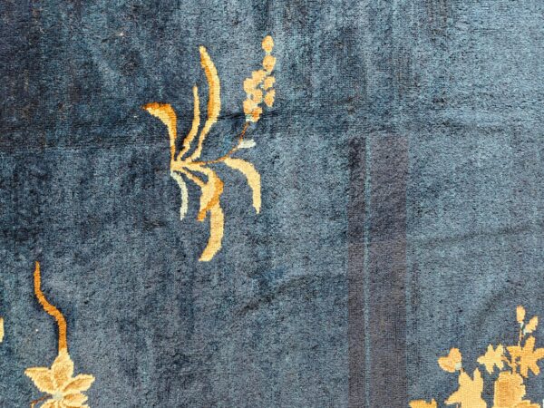 Textured dark blue rug field featuring golden yellow floral designs and a dark vertical stripe detail.