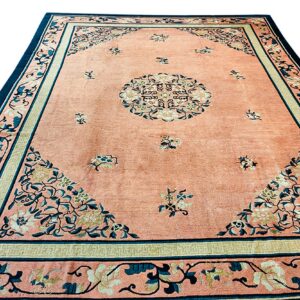 Peach rug with a central medallion, scattered florals, and complex borders in teal and cream.