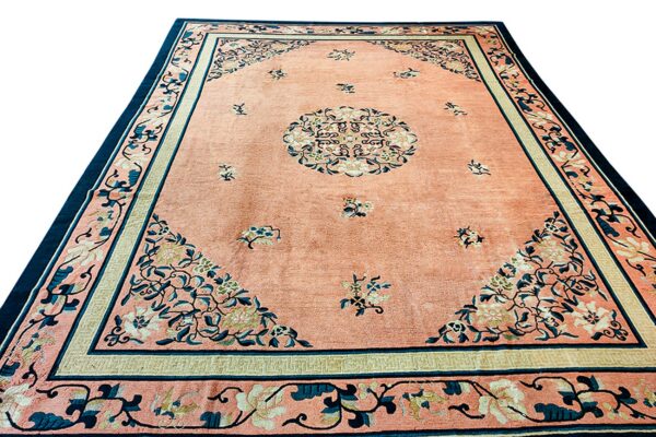 Peach rug with a central medallion, scattered florals, and complex borders in teal and cream.